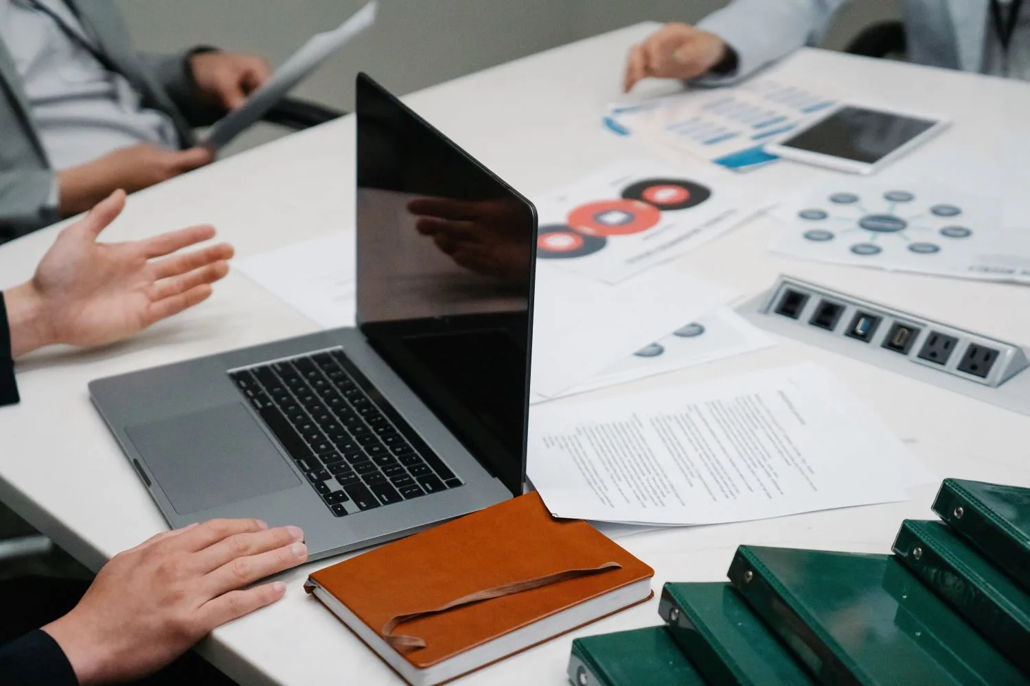 A working discussion around a laptop, printed charts and notebooks